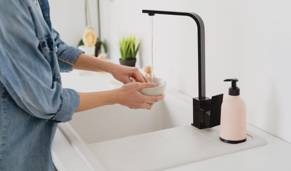 Woman filling a bowl with water in the sink