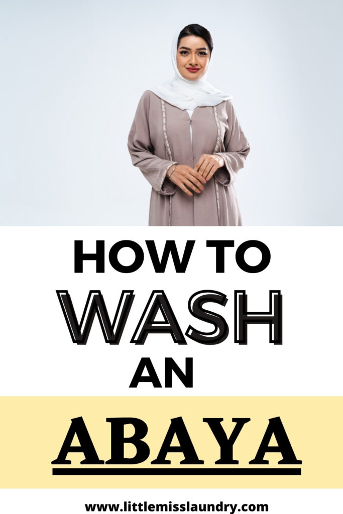 Confident woman in a taupe abaya and white hijab standing against a light background, with bold text overlay stating 'HOW TO WASH AN ABAYA' and the website 'littlemisslaundry.com' at the bottom.