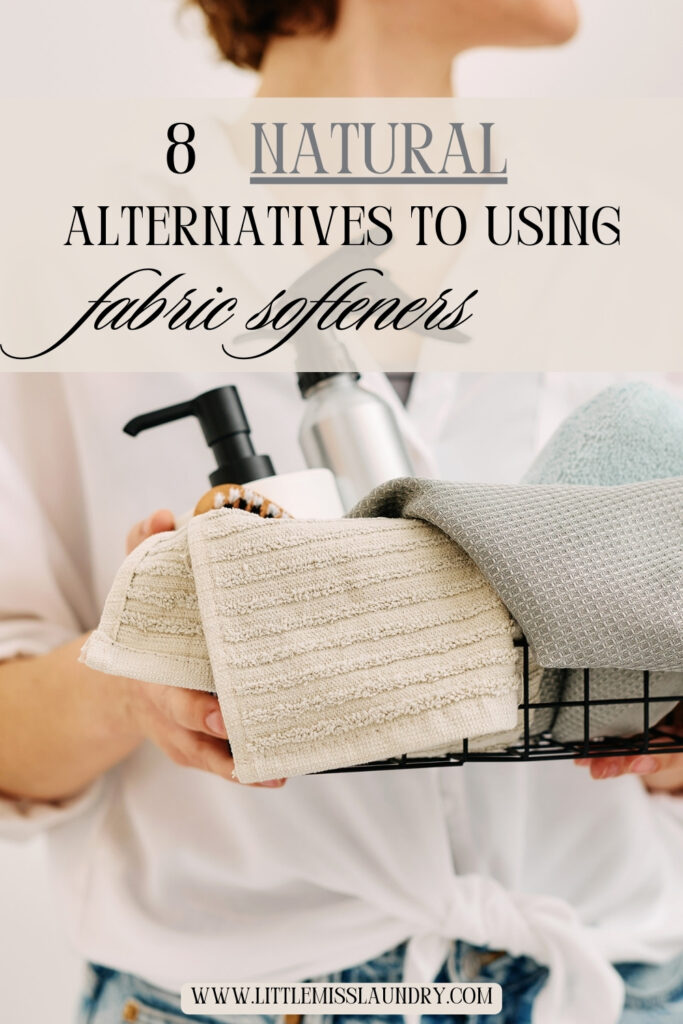 Close-up of a woman holding a wire basket filled with folded towels and eco-friendly cleaning products, with overlay text reading "8 Natural Alternatives to Using Fabric Softeners" and the website littlemisslaundry.com